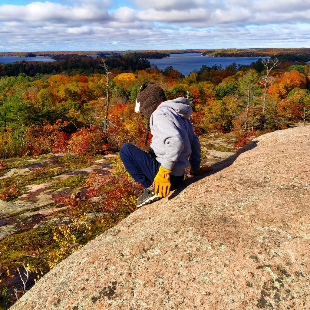 kid on rock of nature walk with great view of autumn leaves