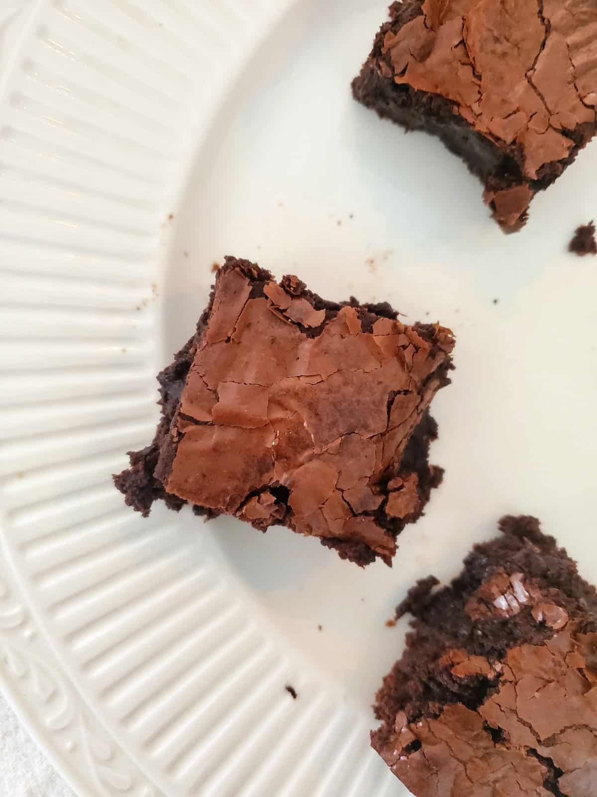 fudgy brownie with crackly top on a white stoneware plate