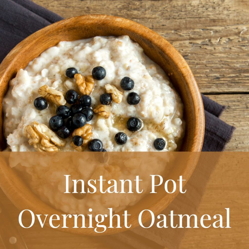 a wooden bowl of oatmeal sits on a rough hewn table with a dark grey cloth under it. there are nuts and blueberries topping the oatmeal.