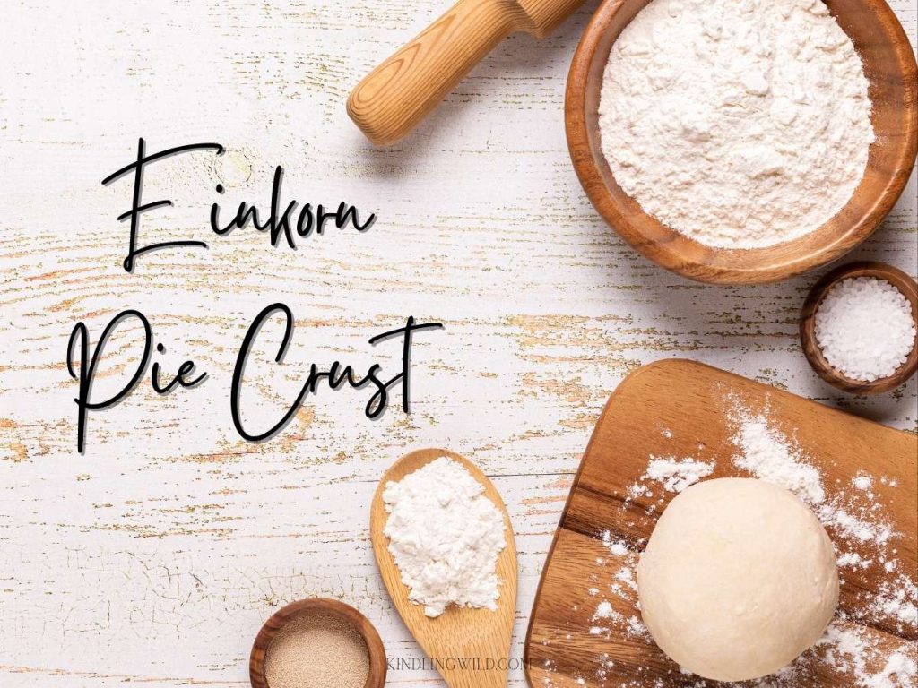 a wooden work surface with wooden rolling pin, pie dough, salt, and flour in wooden bowls and the caption "einkorn pie crust"