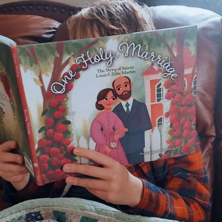 A boy in plaid is sitting holding open a picture book entitled One Holy Marriage
