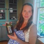 pregnant mom holding a jar of steeping herbs for nora tea
