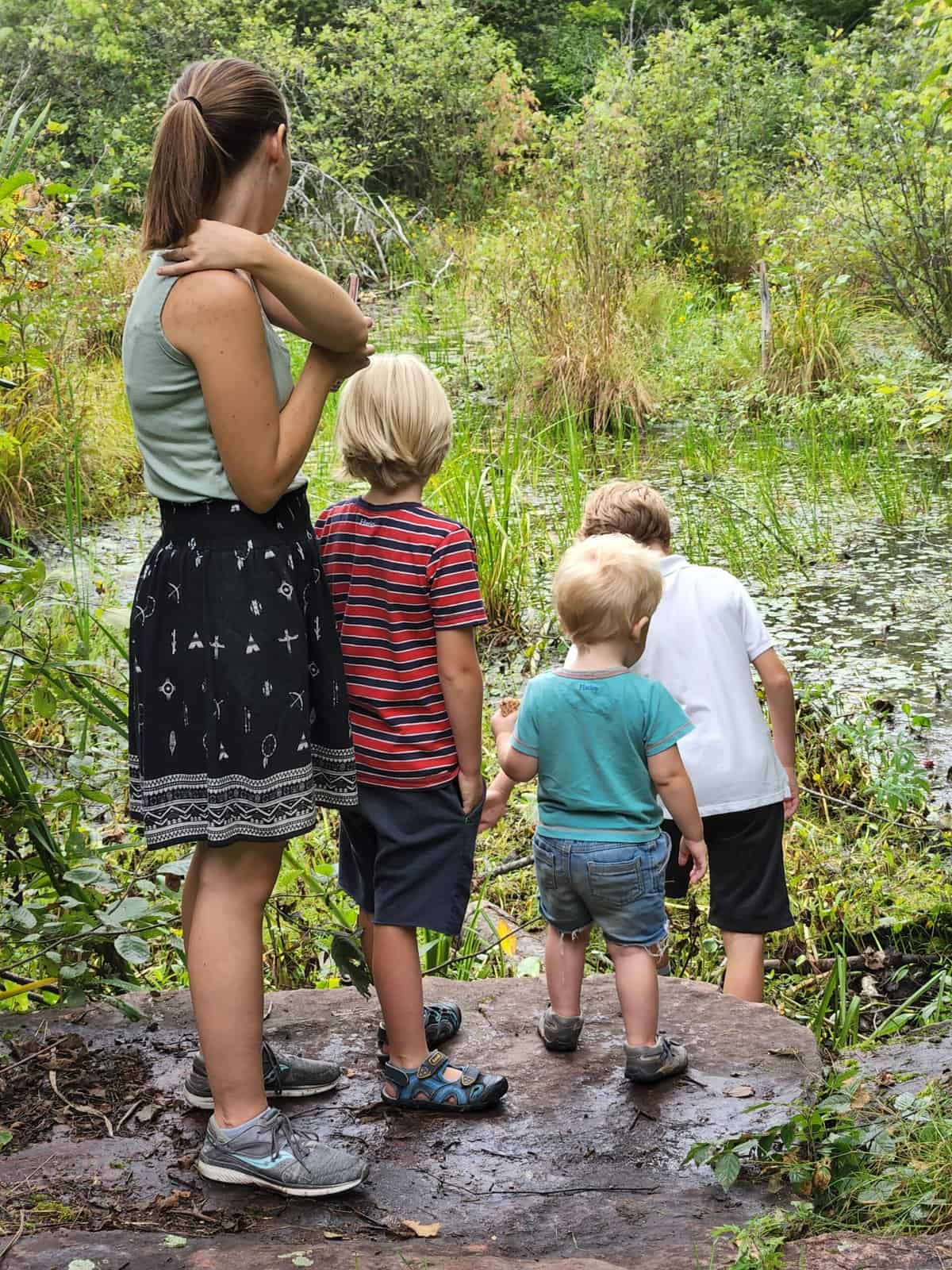 a mom and three kids by a pond